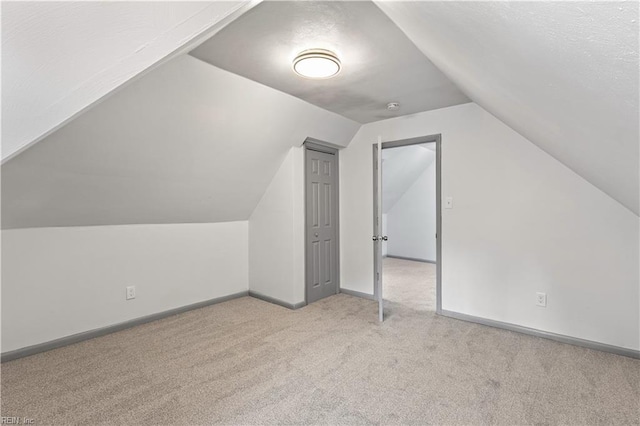 additional living space with vaulted ceiling and light colored carpet