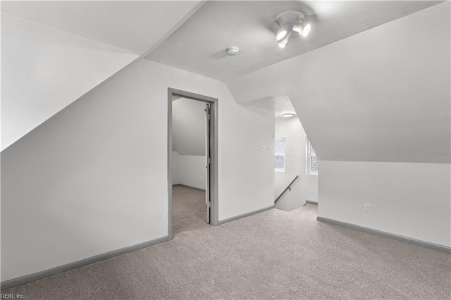 additional living space with light colored carpet and vaulted ceiling