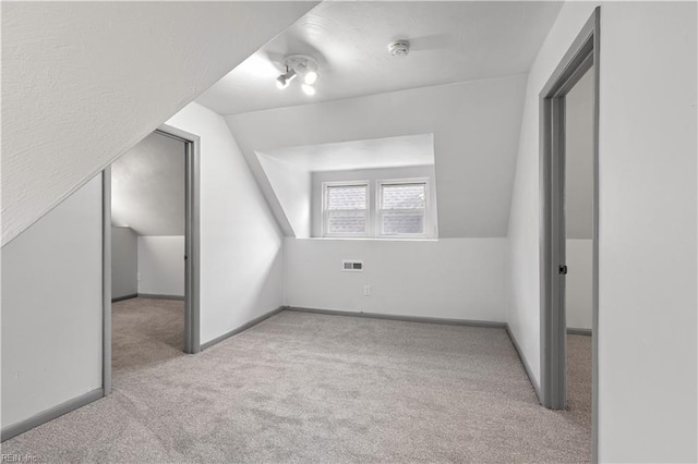 additional living space with vaulted ceiling and light carpet