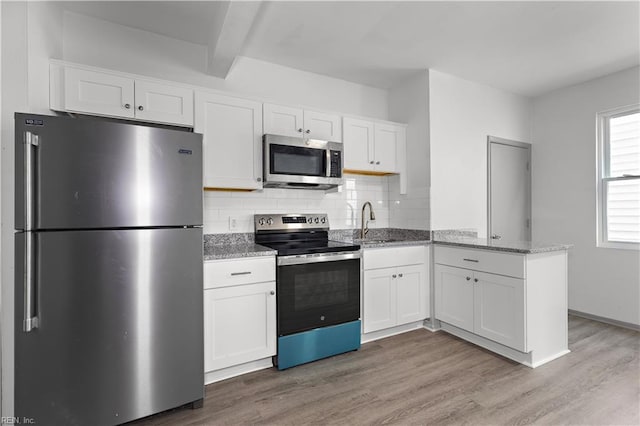 kitchen with appliances with stainless steel finishes, sink, white cabinets, and beamed ceiling