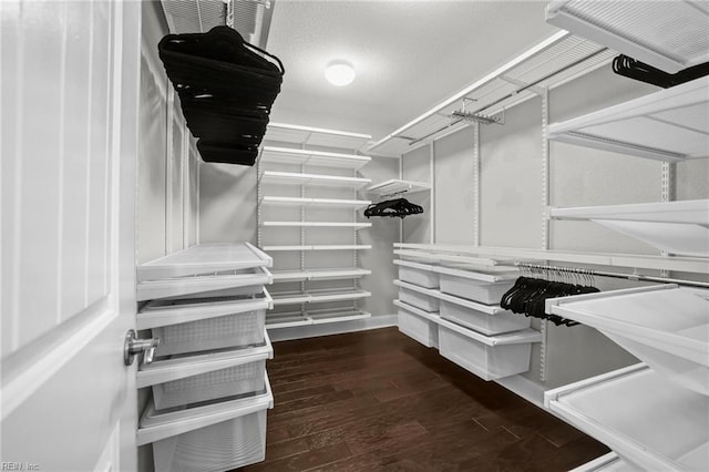 walk in closet with dark hardwood / wood-style floors