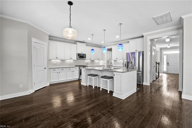 kitchen featuring white cabinets, stainless steel appliances, a kitchen island with sink, and hanging light fixtures