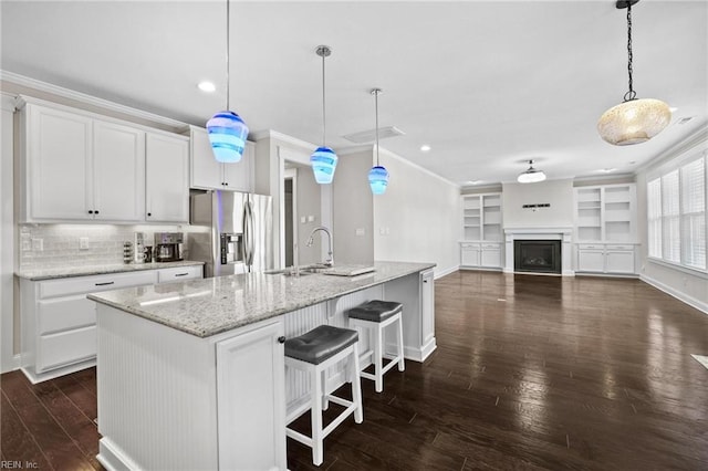 kitchen featuring white cabinets, stainless steel fridge, hanging light fixtures, and a spacious island