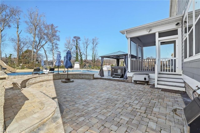 view of patio featuring a swimming pool, a sunroom, and a gazebo