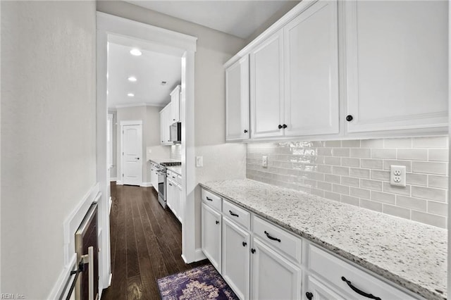 kitchen with white cabinets, stainless steel gas range, light stone countertops, and dark hardwood / wood-style floors