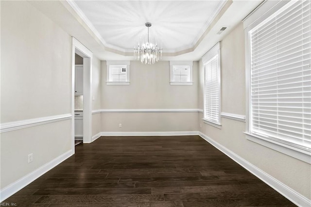 unfurnished dining area with ornamental molding, an inviting chandelier, a tray ceiling, and dark hardwood / wood-style floors