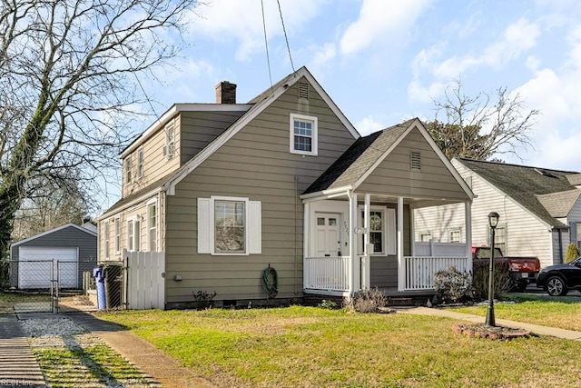 bungalow-style home with a porch, a front lawn, a garage, and an outbuilding