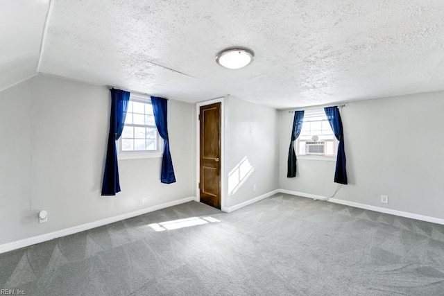 additional living space featuring a textured ceiling, cooling unit, vaulted ceiling, and carpet flooring