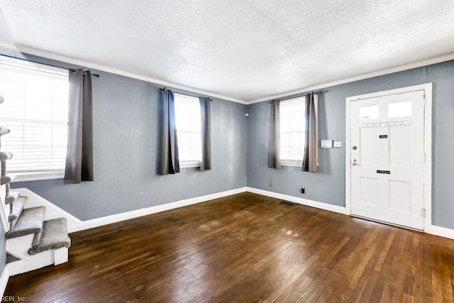 entryway with a textured ceiling, ornamental molding, and dark hardwood / wood-style floors