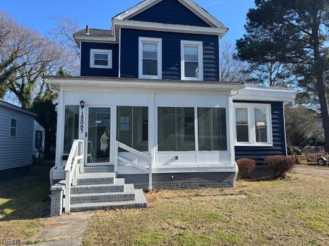 back of property featuring a lawn and a sunroom