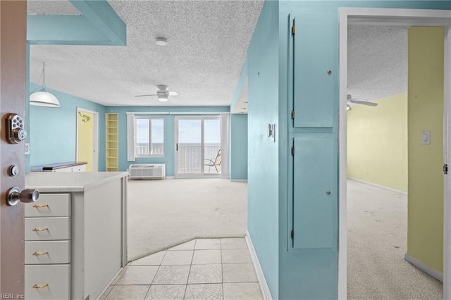 corridor with a textured ceiling, a wall unit AC, and light carpet