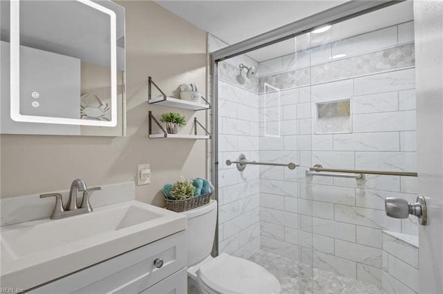 bathroom with toilet, a tile shower, and vanity