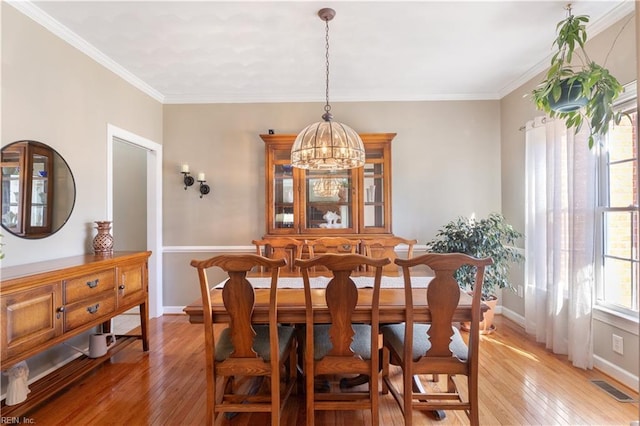 dining room featuring crown molding, an inviting chandelier, and light hardwood / wood-style flooring