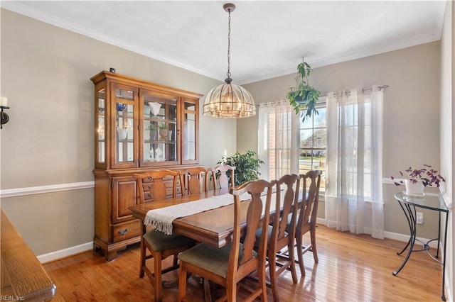 dining room featuring crown molding, an inviting chandelier, and light hardwood / wood-style flooring