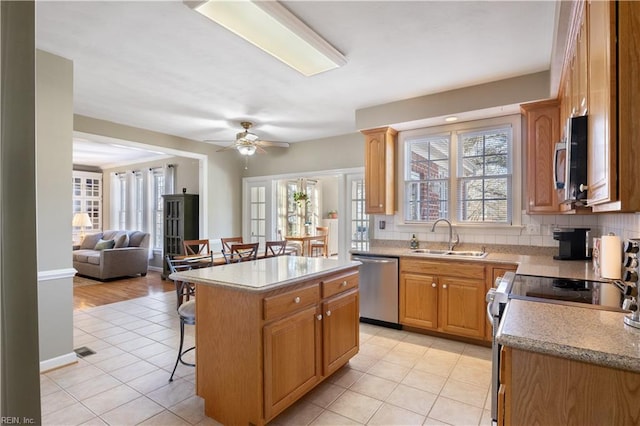 kitchen featuring a center island, a breakfast bar area, appliances with stainless steel finishes, light tile patterned flooring, and sink