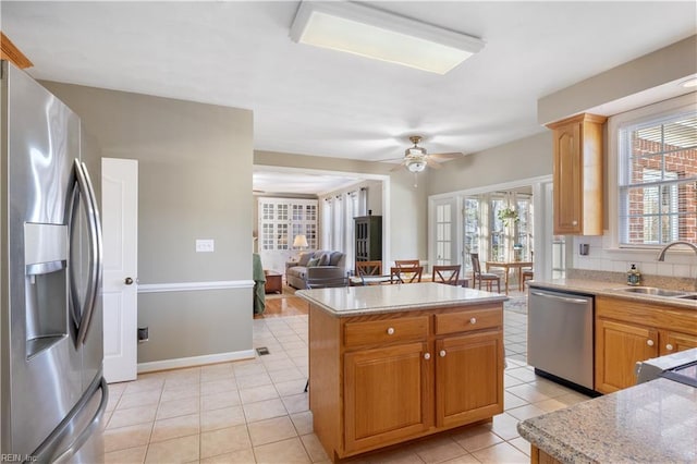 kitchen featuring a center island, stainless steel appliances, light tile patterned floors, ceiling fan, and sink