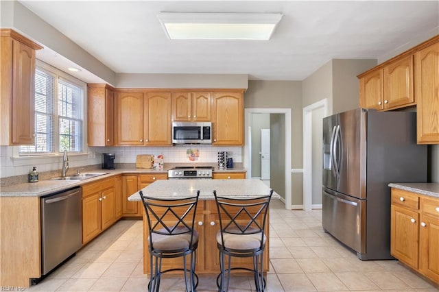 kitchen with a center island, tasteful backsplash, a breakfast bar area, appliances with stainless steel finishes, and sink