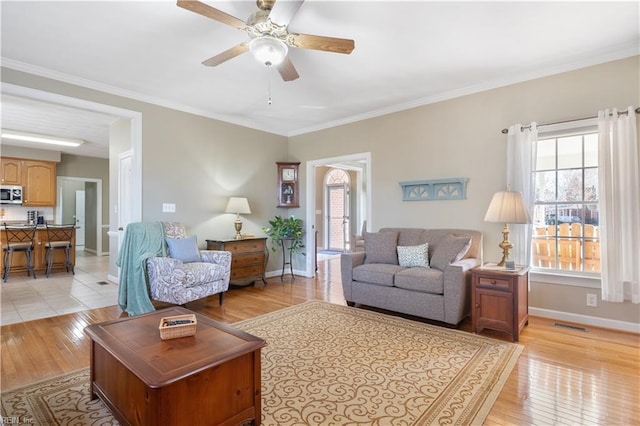 living room featuring light wood-type flooring, ceiling fan, and crown molding