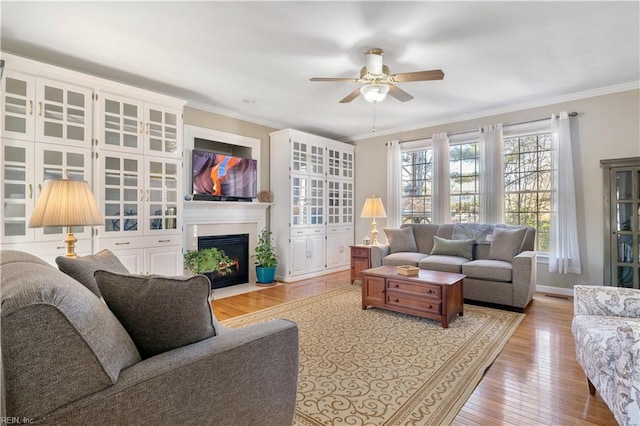 living room featuring ceiling fan, crown molding, and light hardwood / wood-style floors