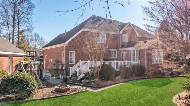 back of property featuring an outdoor fire pit, a yard, and a wooden deck