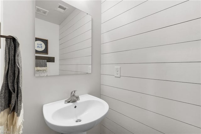 bathroom with sink and wooden walls