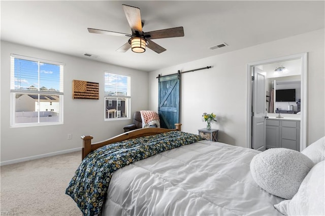 carpeted bedroom featuring ceiling fan, ensuite bath, and a barn door