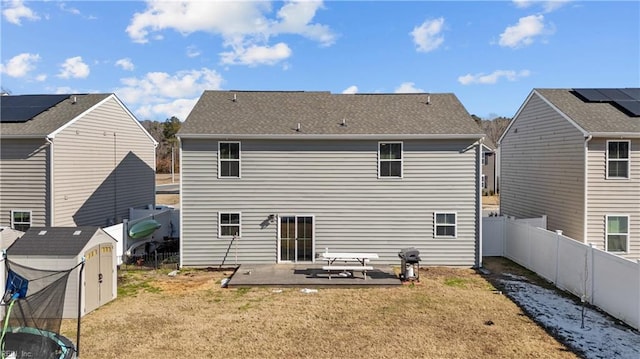 rear view of property featuring a patio area, a yard, and a shed