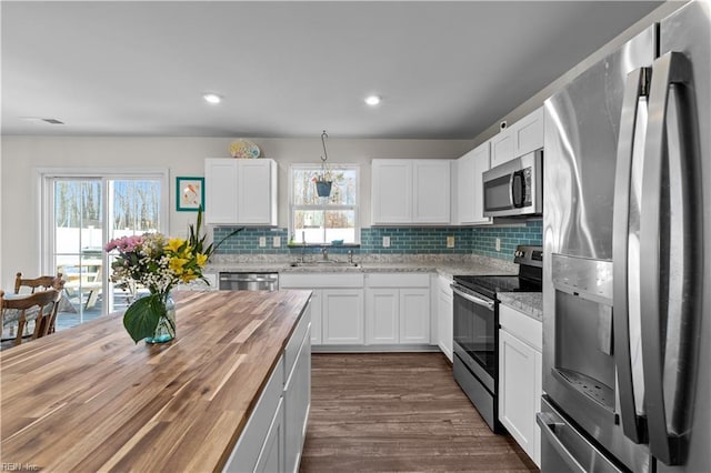 kitchen featuring appliances with stainless steel finishes, white cabinetry, and butcher block countertops