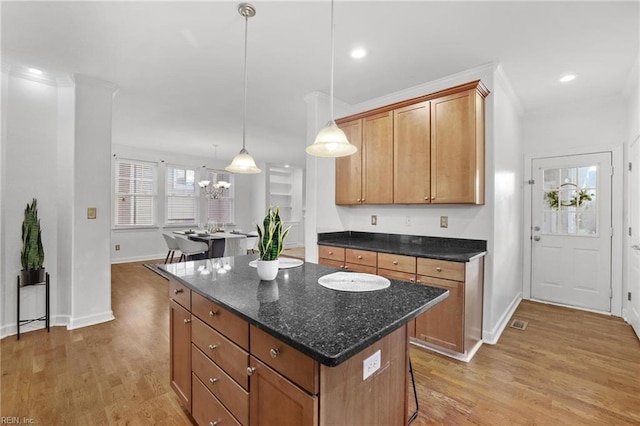 kitchen featuring hardwood / wood-style floors, a notable chandelier, dark stone counters, pendant lighting, and a center island