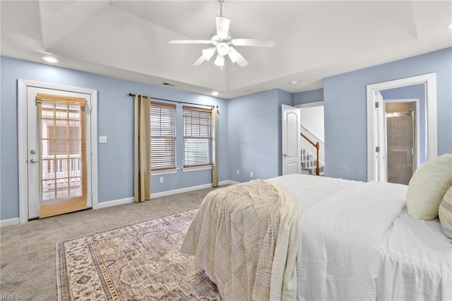 bedroom with ceiling fan, light colored carpet, multiple windows, and a raised ceiling