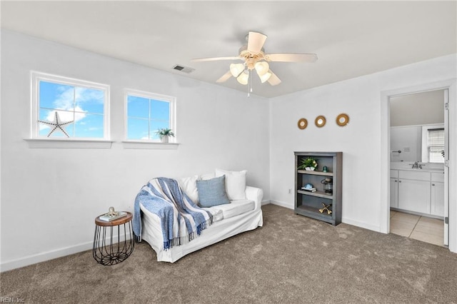 living area featuring ceiling fan, sink, and carpet