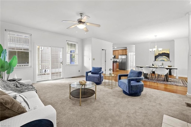 living room with light carpet and ceiling fan with notable chandelier