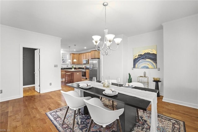 dining space with crown molding, a chandelier, and light wood-type flooring