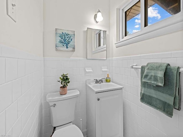 bathroom featuring toilet, vanity, and tile walls