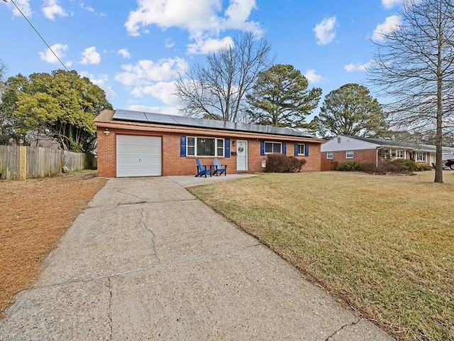 ranch-style house with a garage, a front lawn, and solar panels