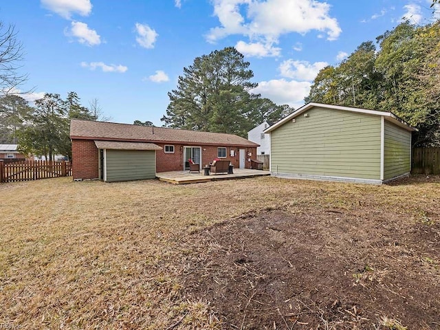 back of house featuring a garage, a wooden deck, and a lawn