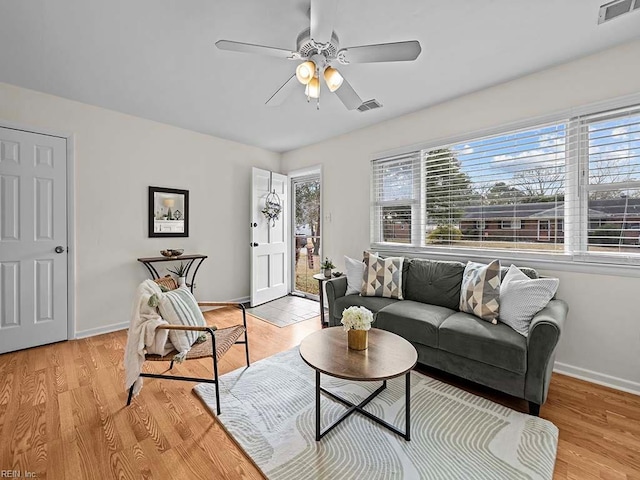 living room with ceiling fan, a wealth of natural light, and light hardwood / wood-style flooring