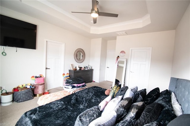 carpeted bedroom with a raised ceiling and ceiling fan