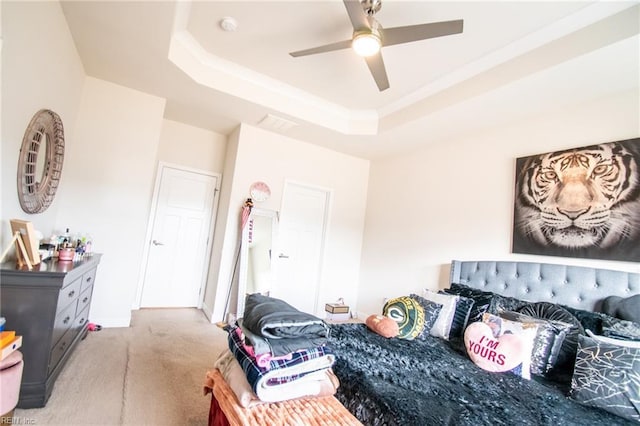 bedroom with light colored carpet, ceiling fan, and a tray ceiling