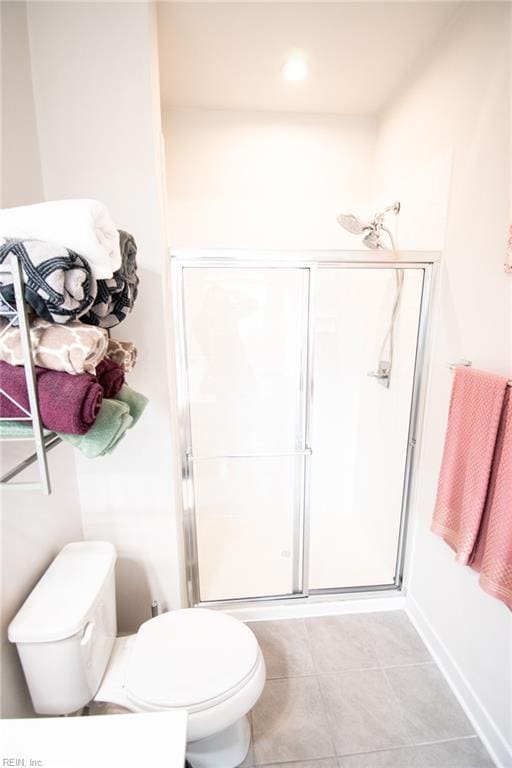 bathroom featuring toilet, tile patterned flooring, and an enclosed shower