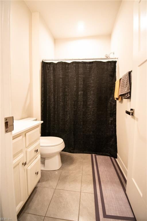 bathroom featuring walk in shower, vanity, tile patterned floors, and toilet