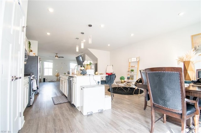 kitchen with a kitchen island with sink, stainless steel appliances, ceiling fan, light hardwood / wood-style flooring, and white cabinetry