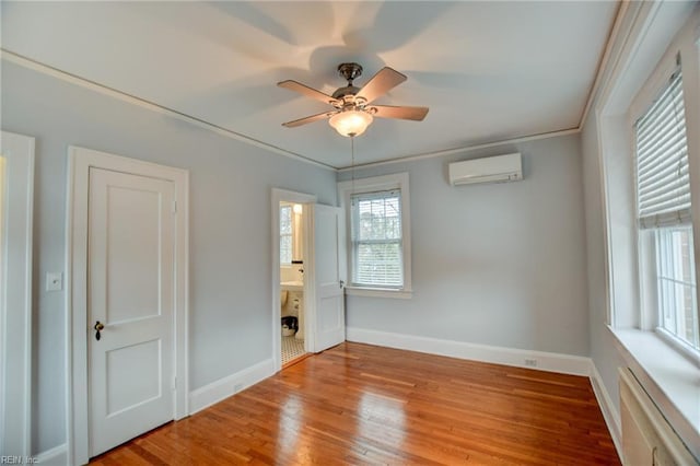 spare room featuring a wall unit AC, ceiling fan, crown molding, and light wood-type flooring