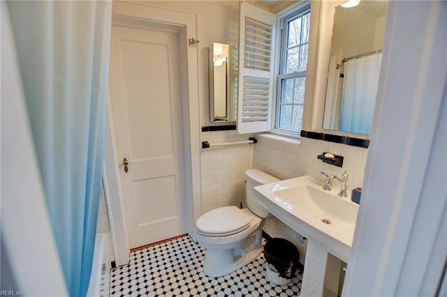 bathroom with toilet, tile walls, sink, and walk in shower