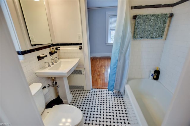 bathroom with tile walls, toilet, radiator, and shower / bathtub combination with curtain