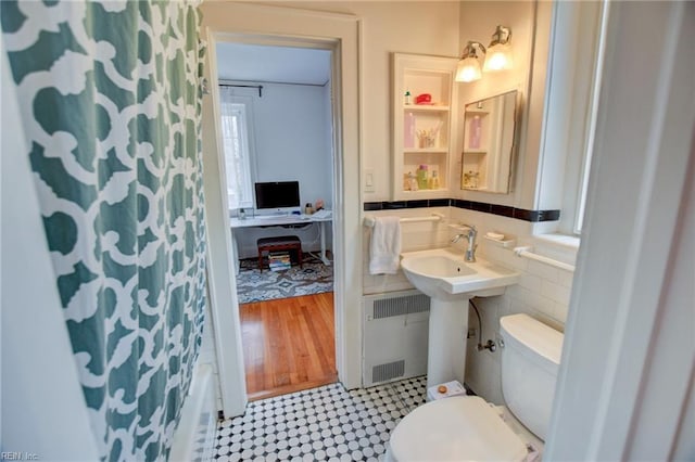 bathroom with toilet, radiator, and tile walls