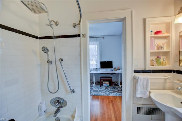 bathroom with radiator, tiled shower / bath combo, hardwood / wood-style flooring, and sink