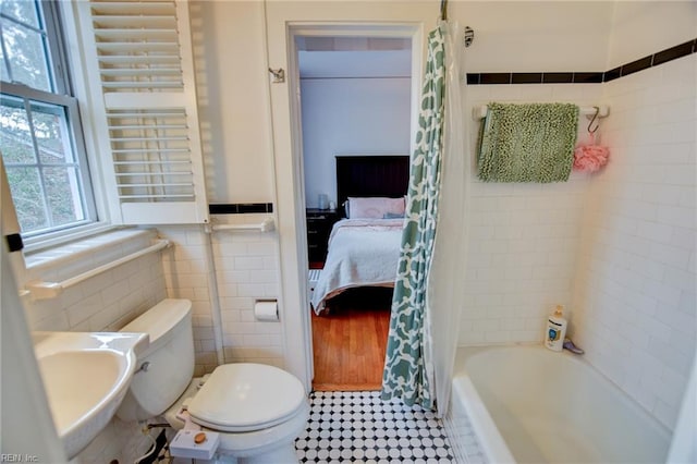 full bathroom featuring toilet, sink, tile walls, and shower / tub combo with curtain