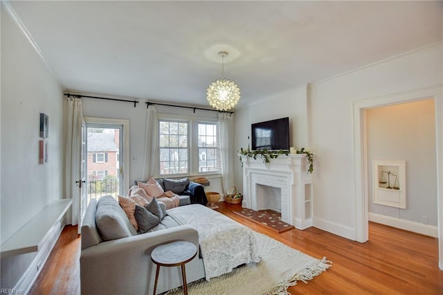 living room featuring crown molding, a fireplace, an inviting chandelier, and hardwood / wood-style flooring