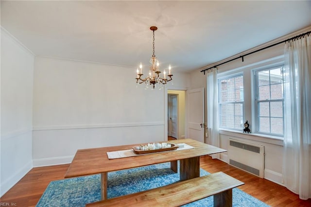 dining area featuring an inviting chandelier, crown molding, wood-type flooring, and radiator heating unit